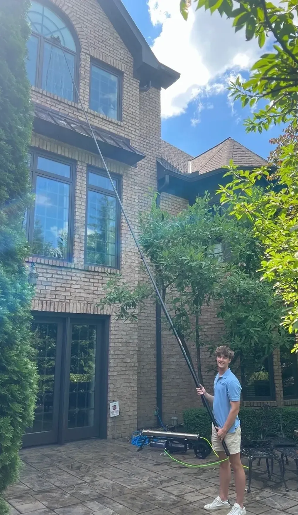Person cleaning tall windows with long pole.