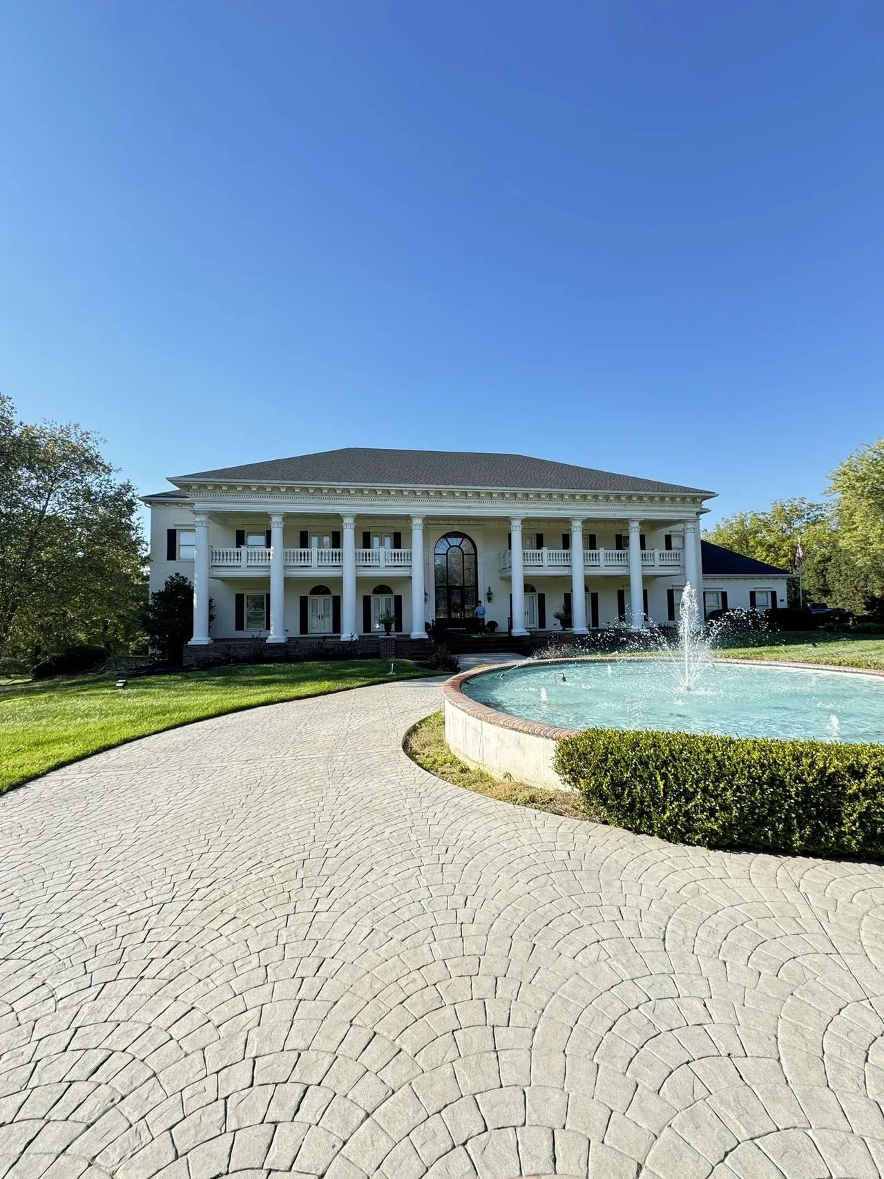 Large mansion with fountain and pathway.
