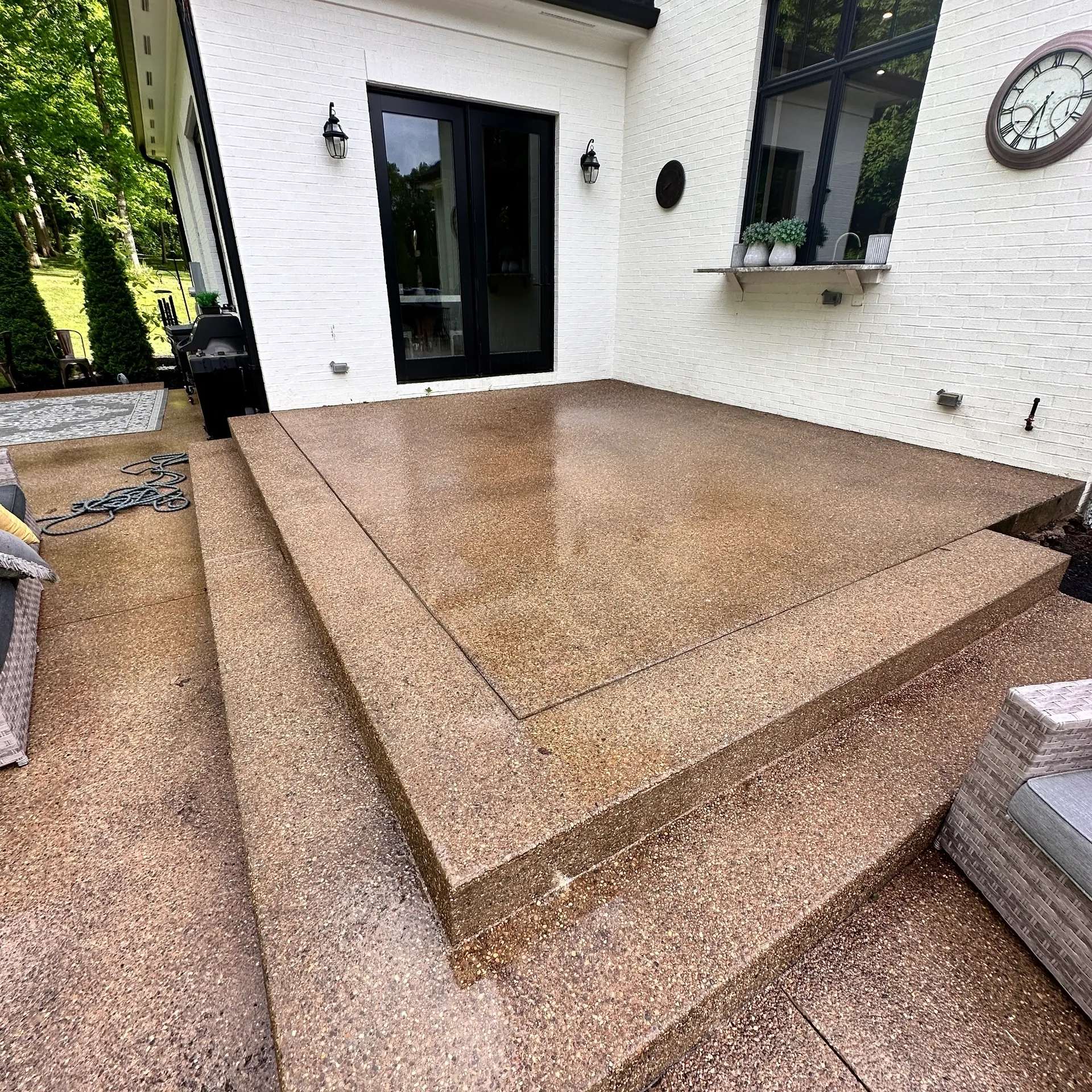 Wet concrete patio with surrounding greenery.