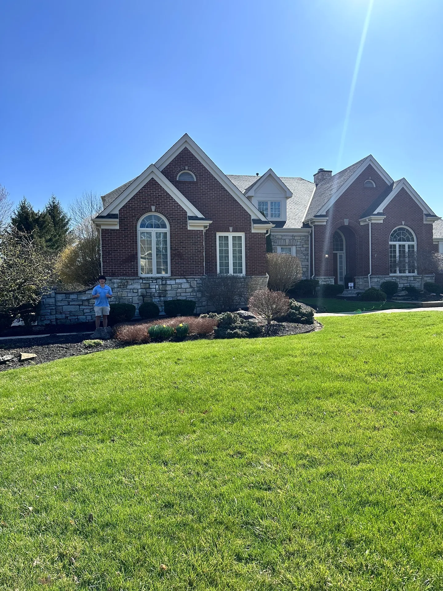 Brick house with green lawn under blue sky.