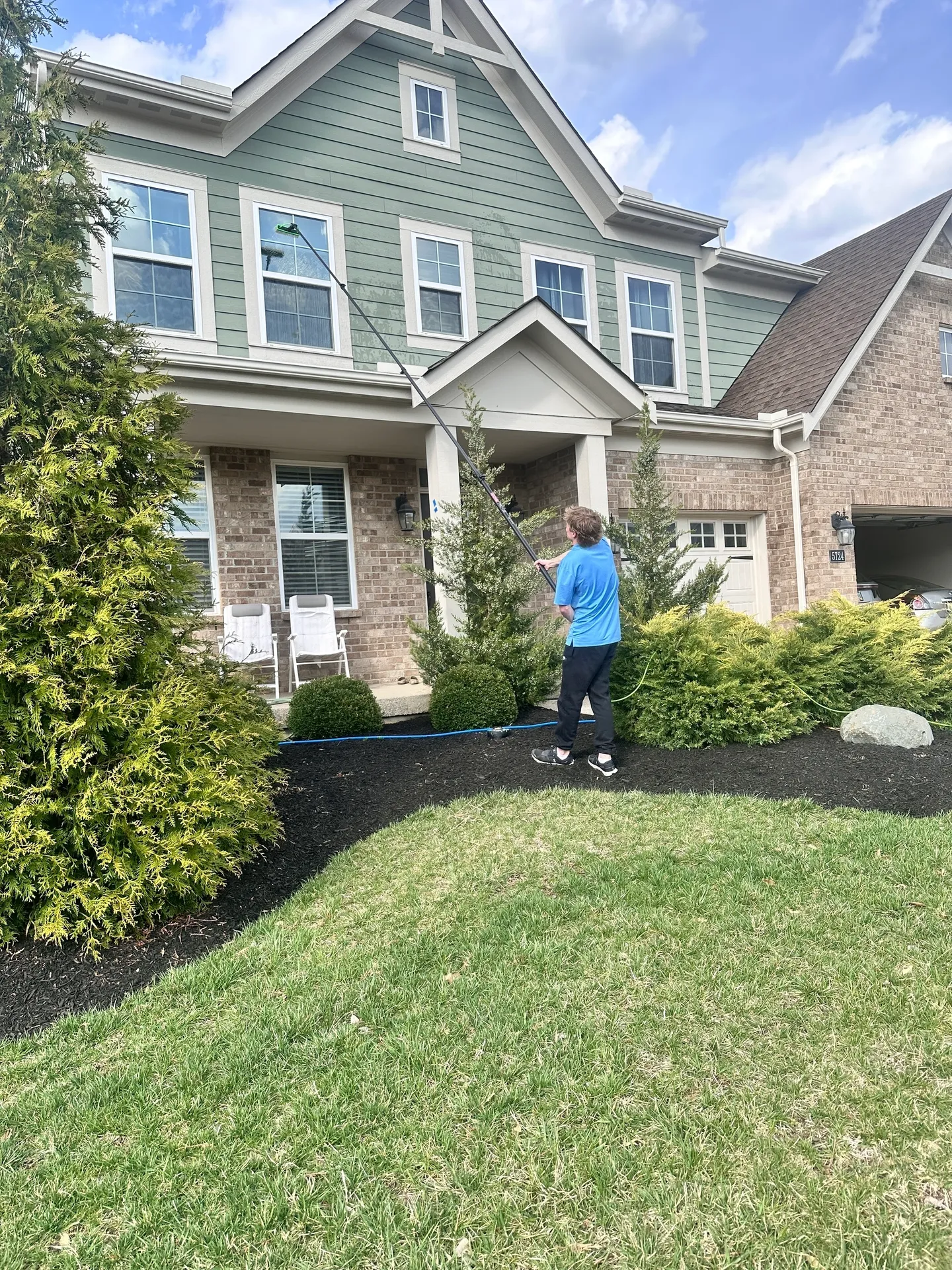 Person cleaning windows of a house exterior.