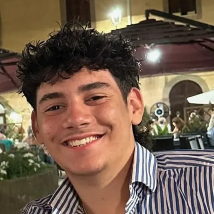 alex Smiling person outdoors wearing striped shirt.