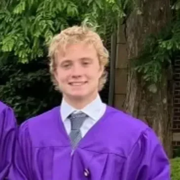 grant Young graduate in purple gown smiling outdoors.