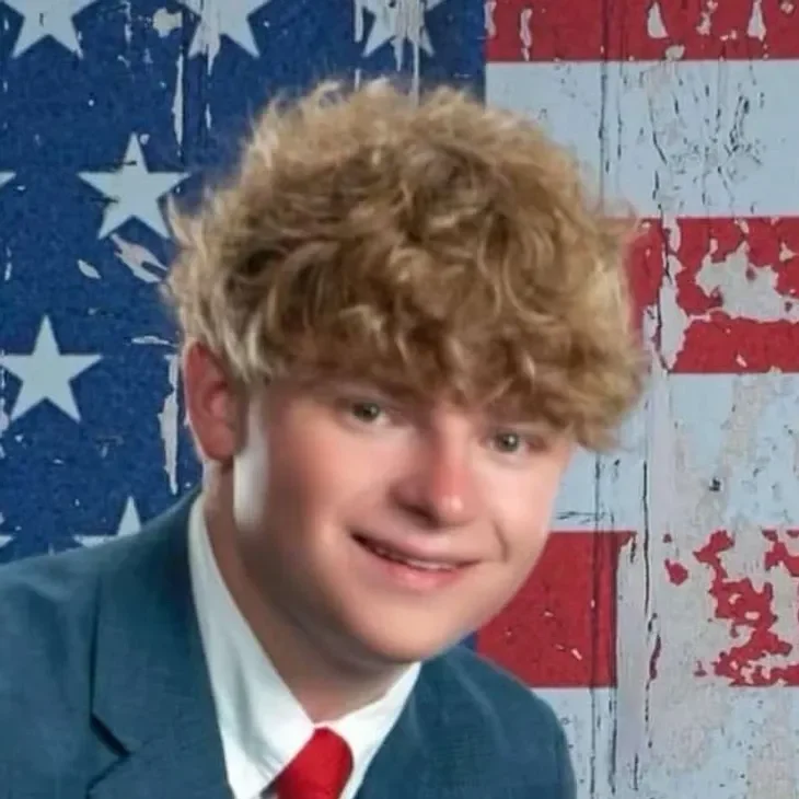 joey Smiling person in suit, American flag background.
